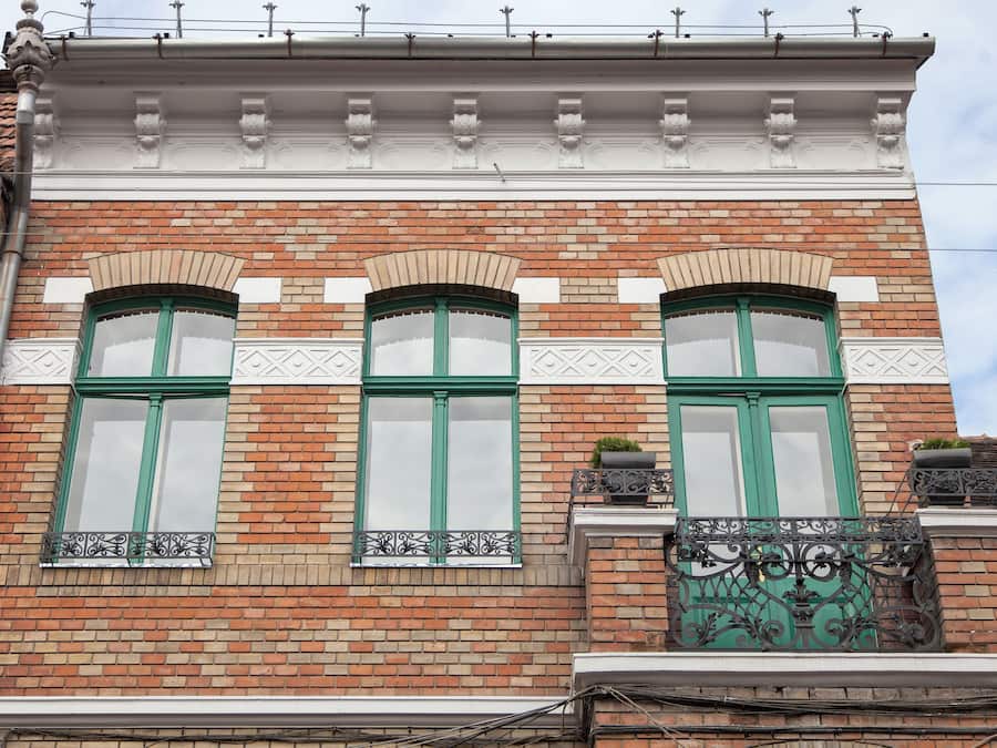 A building facade with three arched windows, a brick wall, and decorative moldings.