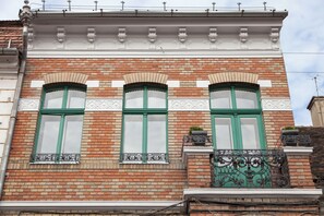 A building facade with three arched windows, a brick wall, and decorative moldings. - Camino Home (Cluj-Napoca)