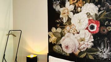 Une chambre à coucher avec un lit, des oreillers, une table de chevet, une lampe et une tapisserie murale.
