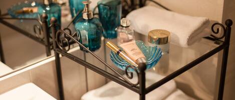 Un mobile bagno con ripiano in vetro che ospita articoli da toilette e un asciugamano bianco.