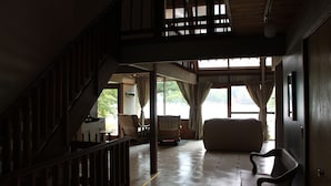 A spacious living area with a high ceiling, wooden staircase, and large windows offering a view of the outdoors. - Lakefront spacious contemporary. Large families welcome. Ski GORE nearby! (Chestertown)