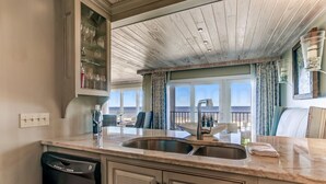 A kitchen with a built-in dishwasher, a sink, and a window overlooking a balcony.