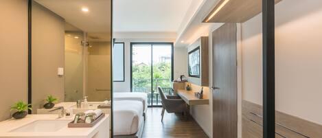 A modern bathroom with a large mirror, a sink, and a shower. There is a bed with a wooden headboard and a bench.