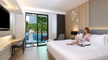 Una habitación de hotel moderna con una cama grande, televisión, escritorio y vista a una piscina.