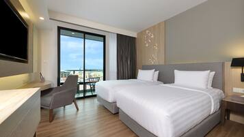 A modern hotel room with a large bed, a desk, and a chair. There is a large window with a view of the city.