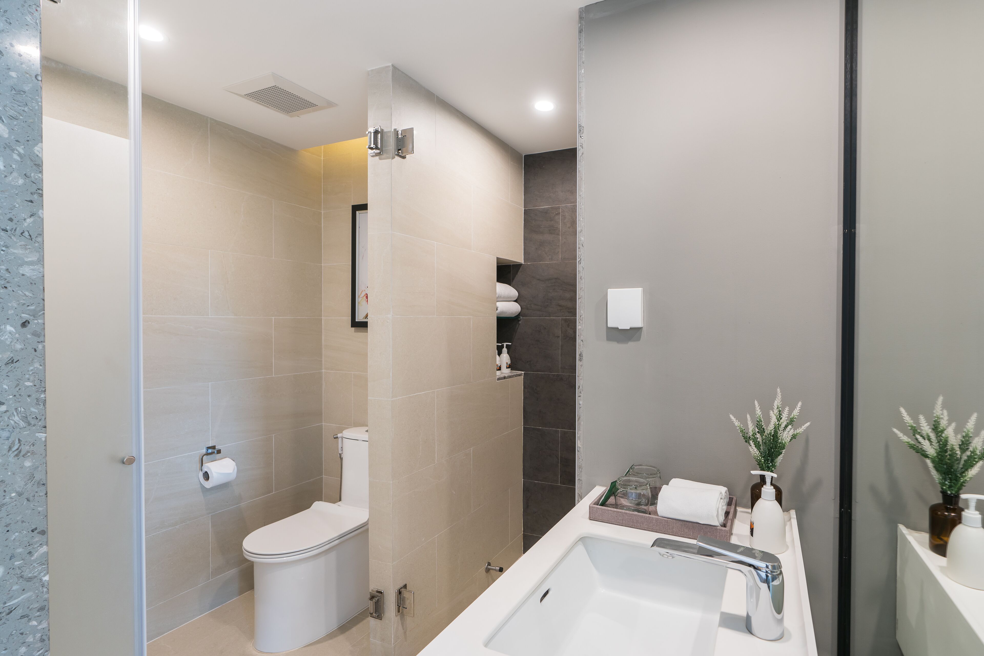 A modern bathroom with a shower, toilet, and sink.
