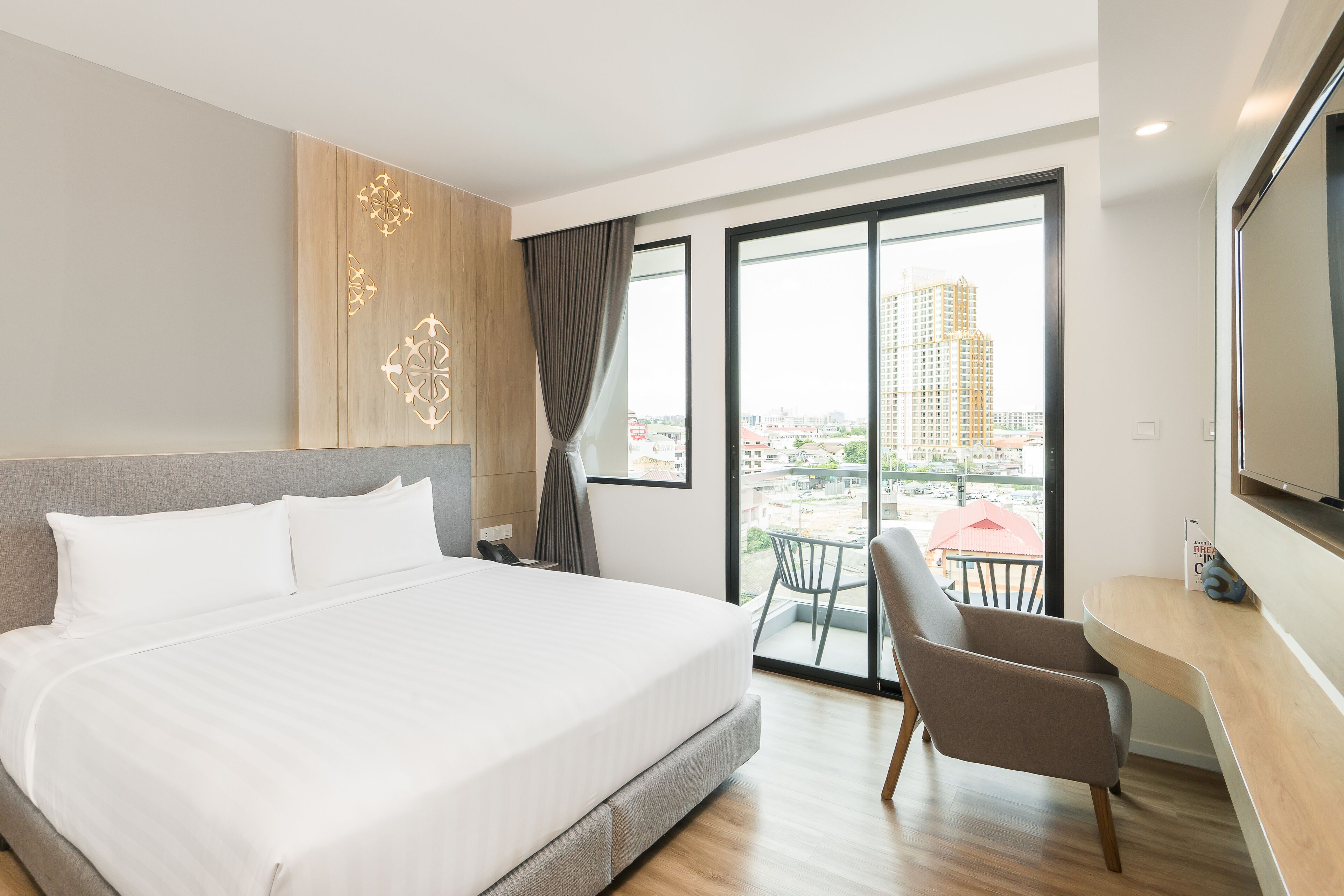 Ein modernes Hotelzimmer mit einem großen Bett, einem Schreibtisch und einem Balkon mit Blick auf die Stadt.