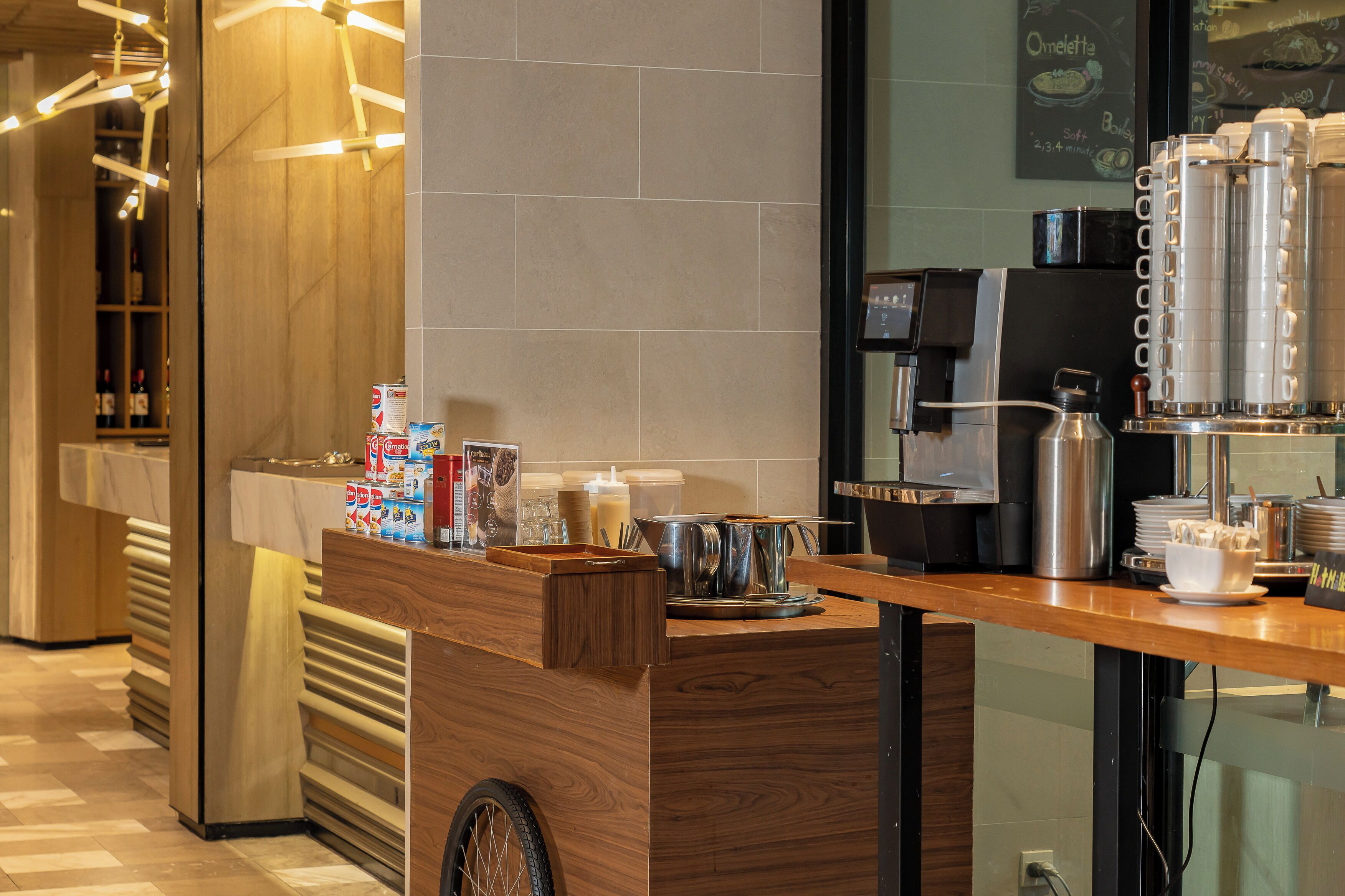 A coffee station with a wooden counter, coffee machines, and various coffee-related items.