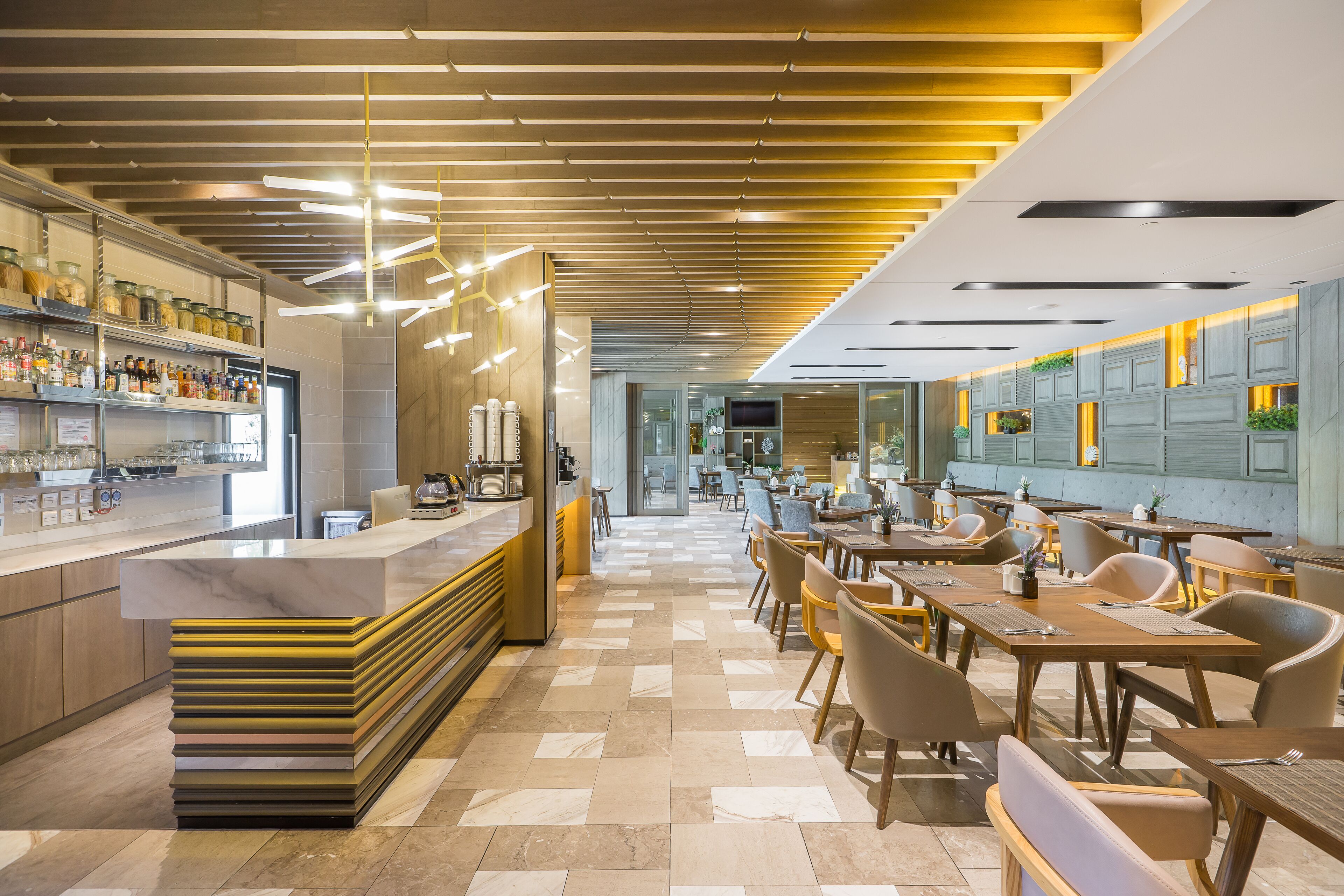 A modern restaurant with a long counter, multiple seating areas, and a checkered floor.