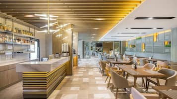 A modern restaurant with a long counter, multiple seating areas, and a checkered floor.