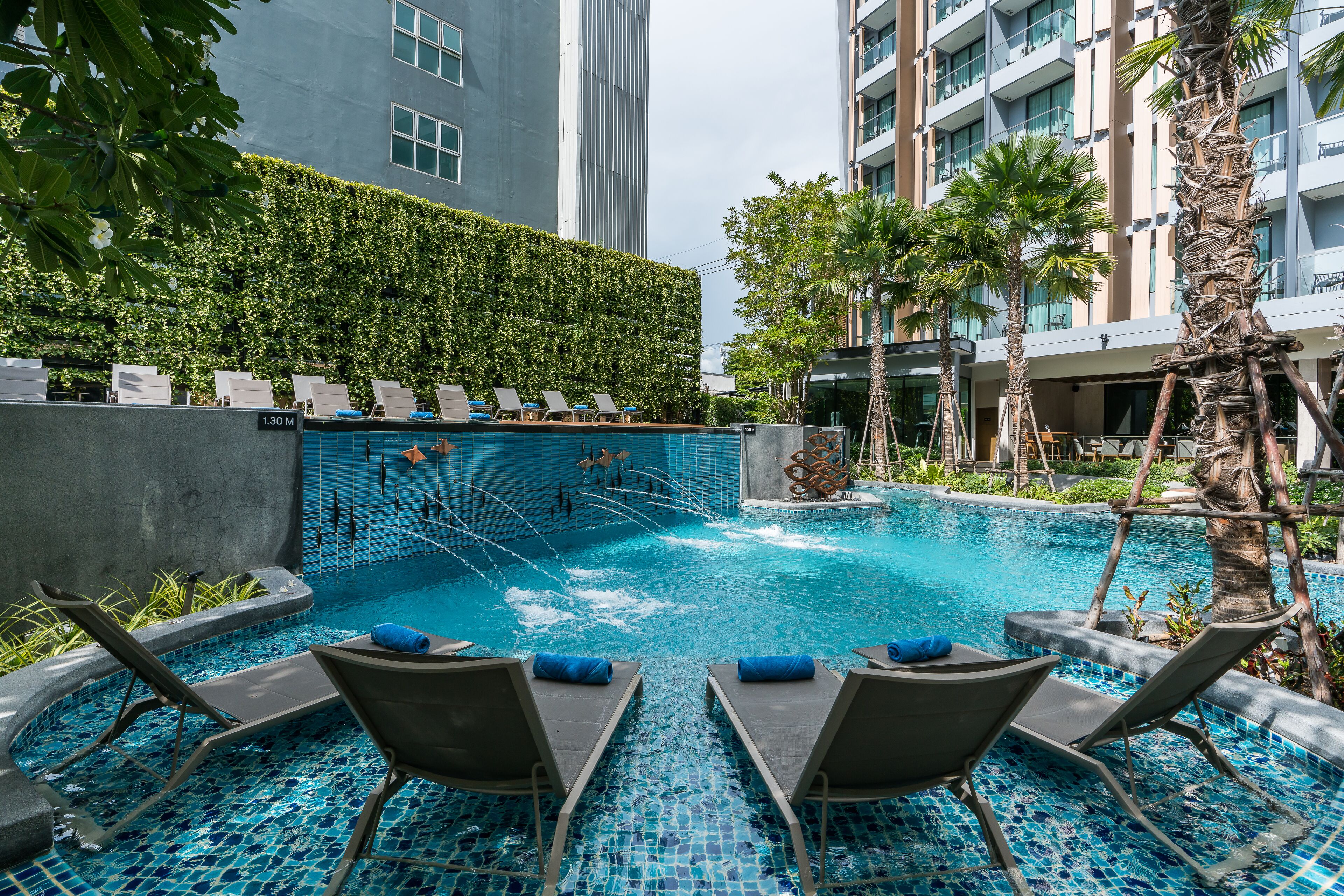 Uma piscina com espreguiçadeiras e um prédio alto ao fundo.