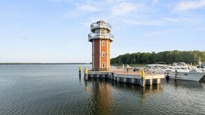 A lighthouse on a dock with boats and a forested shoreline. - Plau Lagoons (Plau am See)