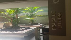 A reception area with a sign reading "PRÁGADA DE LEITURA" and a glass partition. - Holandas Prime (João Pessoa)