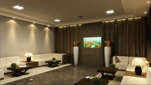 A modern living room with a large TV screen, two sofas, a coffee table, and a lamp. - Holandas Prime (João Pessoa)
