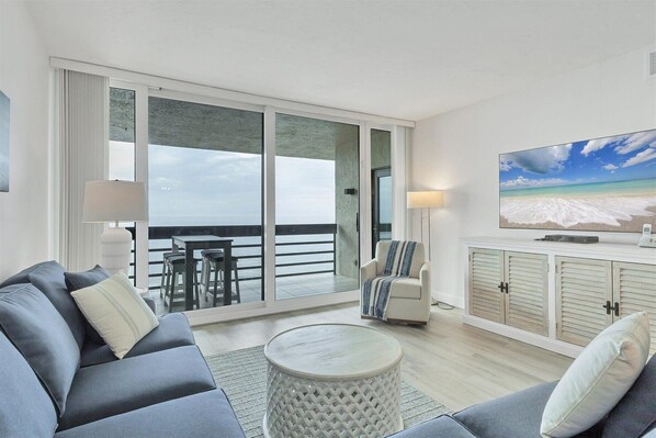 A modern living room with a sofa, a coffee table, and a TV on a wall.