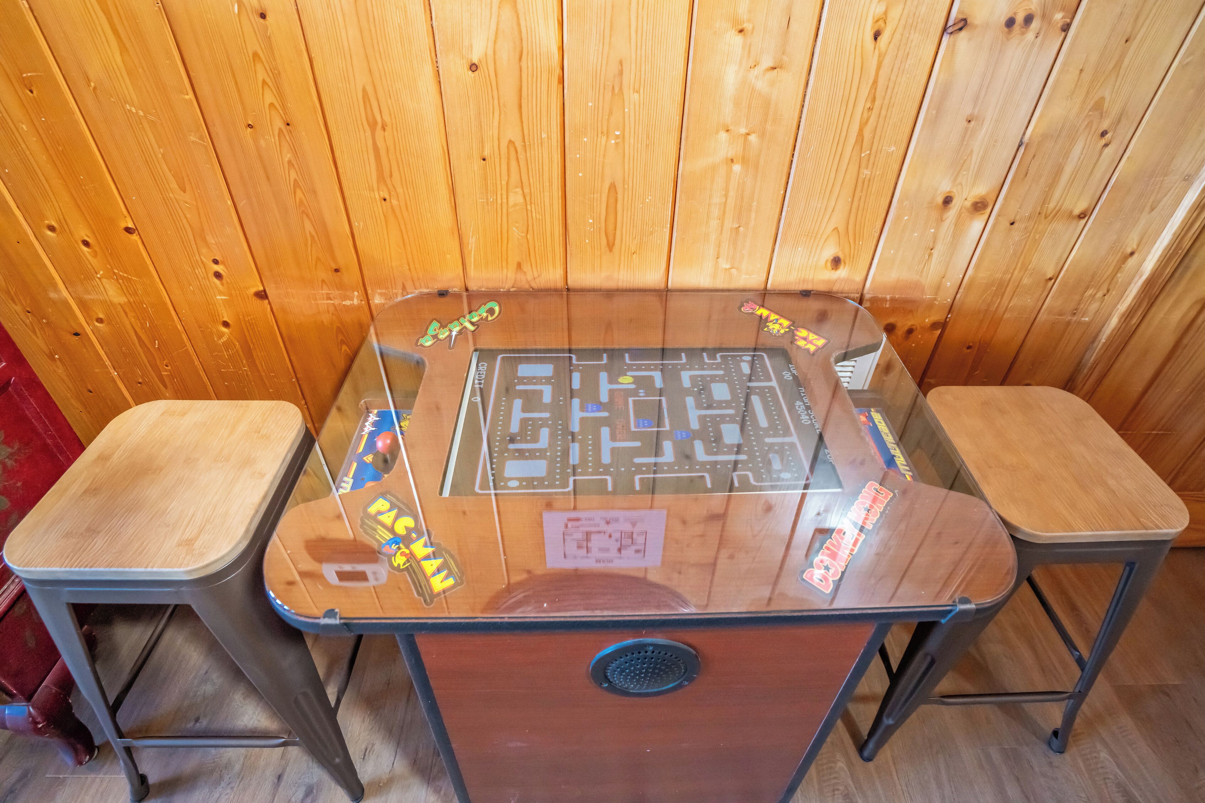 A wooden-paneled room with a glass-top table featuring a maze game, two wooden chairs, and a vent.
