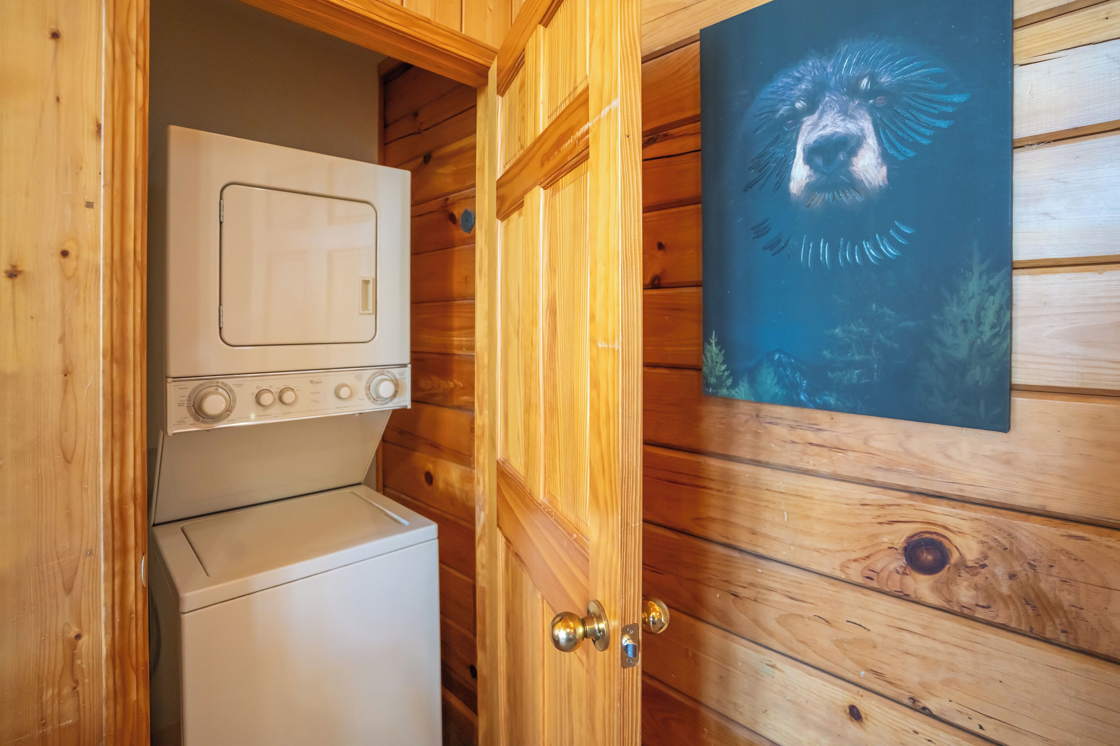 A wooden interior with a washing machine and a door with a poster.