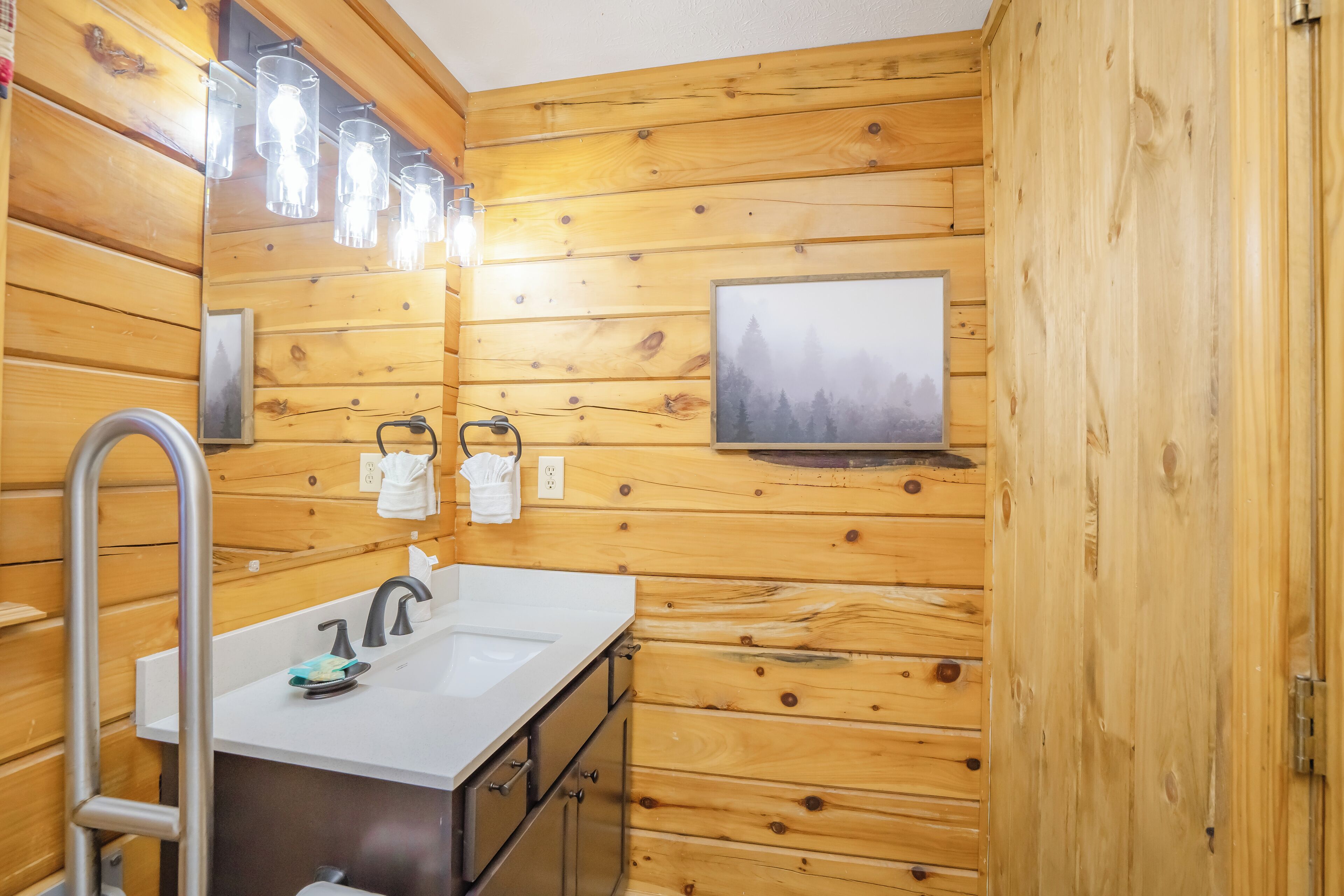 A wooden-paneled bathroom with a sink, faucet, and towel rack.
