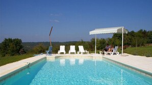 A swimming pool with clear blue water, surrounded by white lounge chairs and a white pergola. - Cottage for 2 or 4 p refurbished in an old fortified farm from the 17th century (Saint-Amand-de-Coly)