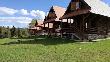 A log cabin with a stone foundation, wooden exterior, and a steeply pitched roof.