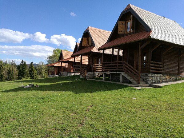 A log cabin with a stone foundation, wooden exterior, and a steeply pitched roof.