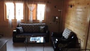 A cozy cabin interior with a sofa, armchair, and a small table. - Lodge Nagramak (Bajina Bašta)