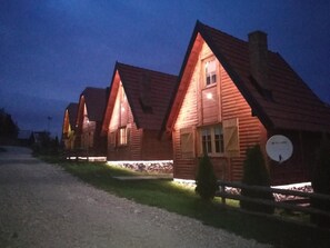 A row of log cabins with pitched roofs and a gravel path in front.