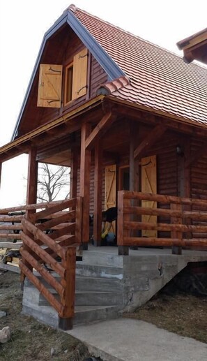 A wooden cabin with a porch and a staircase leading to the entrance.
