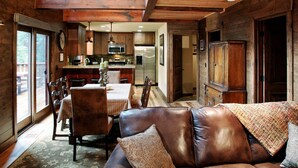 Interior acogedor de una cabaña con comedor, cocina y un sofá de cuero.