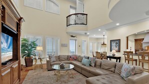 A spacious living room with a large sectional sofa, a glass coffee table, and a potted plant.