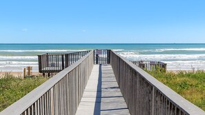 A wooden boardwalk leading to the beach with a clear view of the ocean.