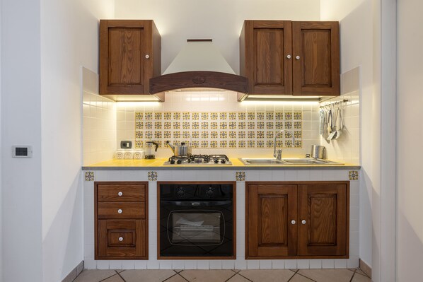 Una cocina con armarios de madera, estufa, horno y salpicadero de azulejos.