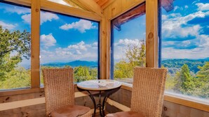A cozy room with wicker chairs and a small table, large windows offering a scenic view of mountains and trees. - 🐻Beau Voir🚡 Beautiful Views, Game Loft, Great Location, & Hot Tub (Sevierville)