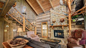 A rustic interior with a stone fireplace, wooden staircase, and cozy seating areas. - 🐻Beau Voir🚡 Beautiful Views, Game Loft, Great Location, & Hot Tub (Sevierville)