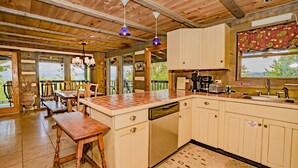 A wooden interior with a kitchen, dining area, and a view of the outdoors. - 🐻Beau Voir🚡 Beautiful Views, Game Loft, Great Location, & Hot Tub (Sevierville)