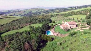 Une propriété rurale dotée d’une piscine, entourée de collines verdoyantes et comprenant une grande maison.