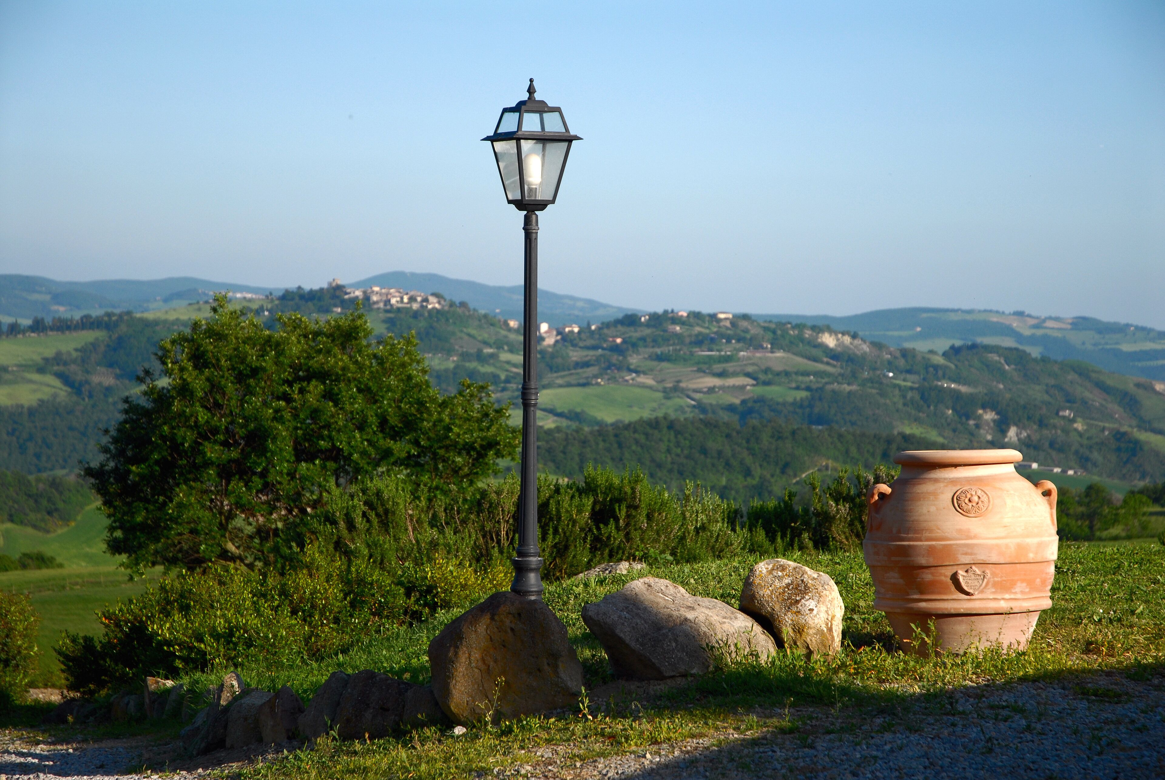 Landelijk landschap met een lantaarnpaal en een grote terracotta pot.