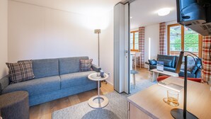Una sala moderna con un sofá gris, una mesita redonda y una lámpara de pie.