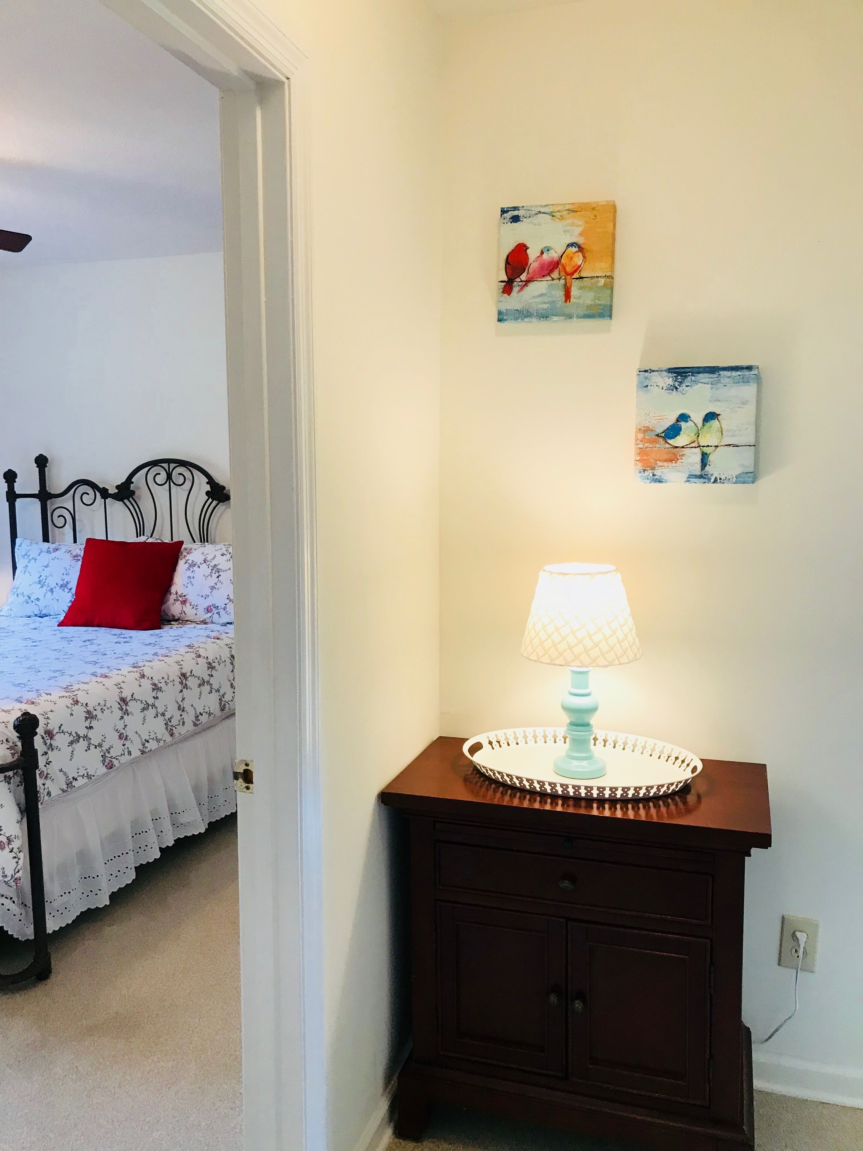 Une chambre à coucher avec un lit, une table de chevet avec une lampe et deux œuvres d’art murales.