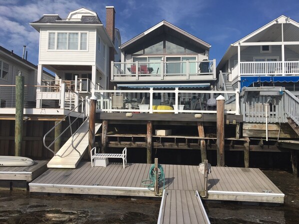 A waterfront property with a dock, a covered deck, and a house with multiple levels and balconies.