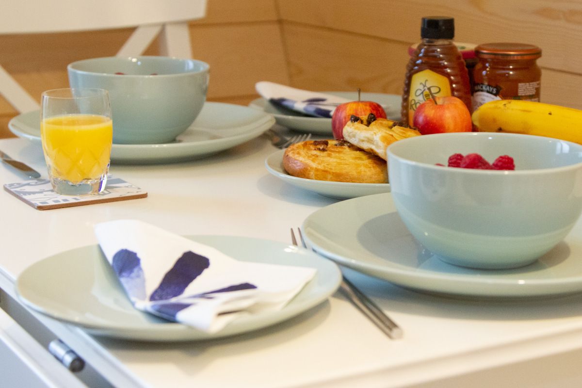 A breakfast setting with plates, bowls, and a glass of orange juice.