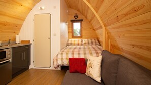 Una habitación acogedora con una cama en literas, una pequeña kitchenette y un techo de madera.