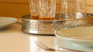 Una mesa con una botella de vidrio transparente, un decantador de vidrio y varios vasos de cristal sobre una bandeja de plata.