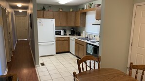 A kitchen with wooden cabinets, a white refrigerator, a microwave, and a sink.