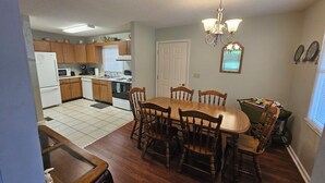 A kitchen with wooden cabinets, a dining table with chairs, a refrigerator, and a microwave.