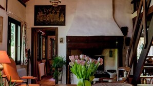 A cozy room with a wooden table, a vase of flowers, and a fireplace.