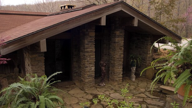 Un edificio de piedra con techo inclinado y una escalera de piedra que lleva a una puerta.