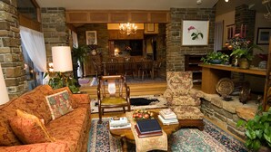 Una sala de estar acogedora con sofá, sillón y mesa de centro, que incluye chimenea, comedor y varios objetos decorativos.