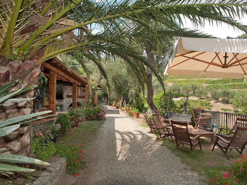 Un sentiero di giardino che conduce a una struttura in legno con posti a sedere all'aperto e un grande ombrellone.