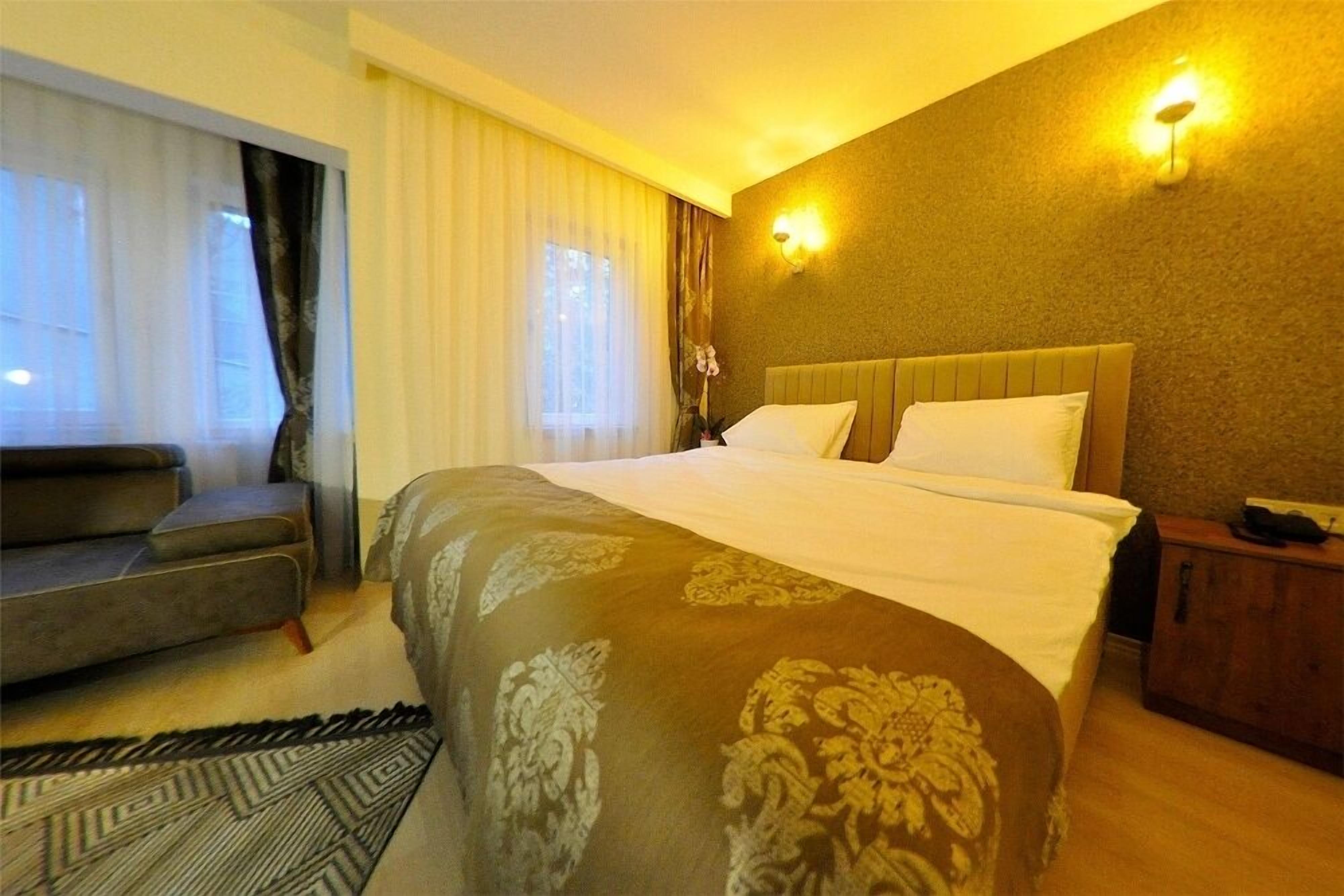 A hotel room with a large bed, a sofa, and a nightstand.